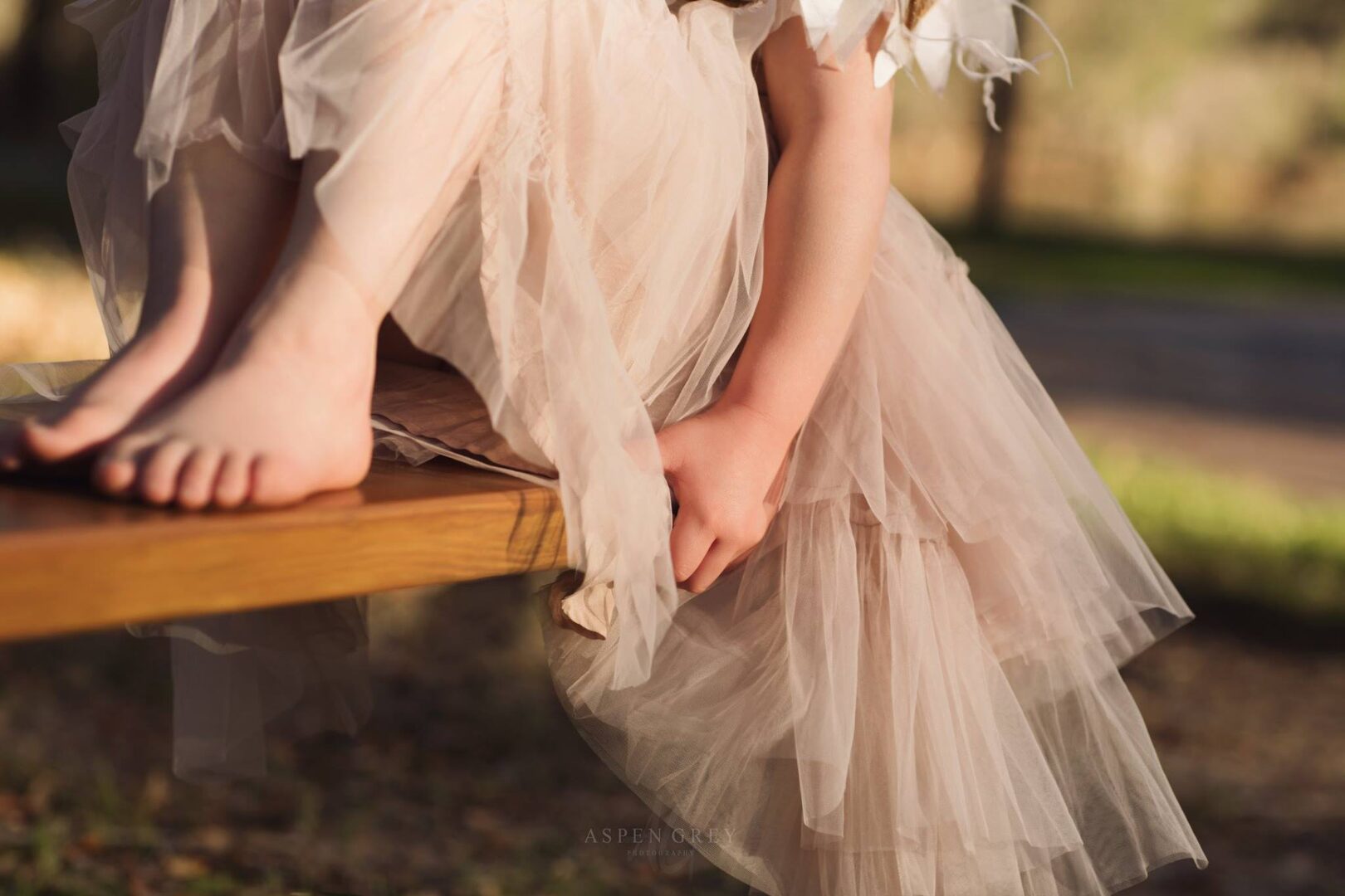 Girl in tulle dress sits on bench.