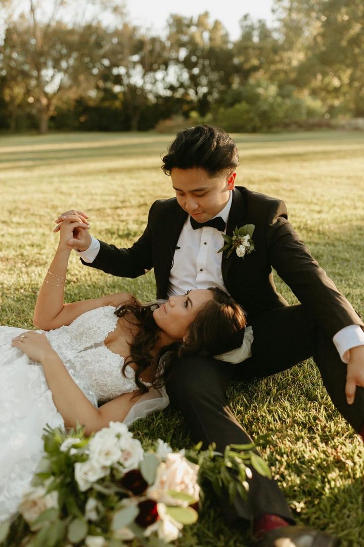 Bride and groom embrace on grass.
