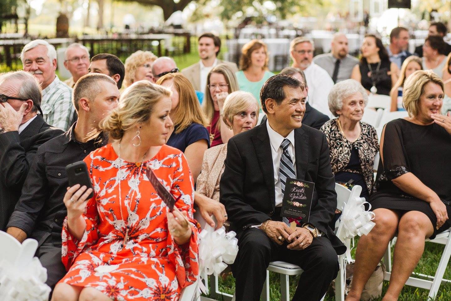 Wedding guests seated outdoors at ceremony.