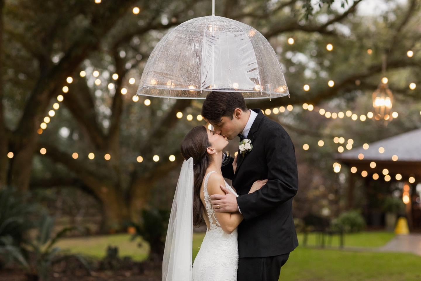 Bride and groom kissing under umbrella.