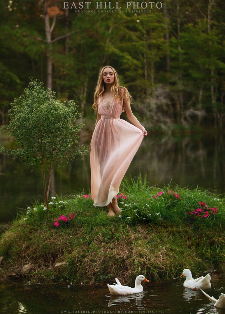 Woman in pink dress by water with ducks.