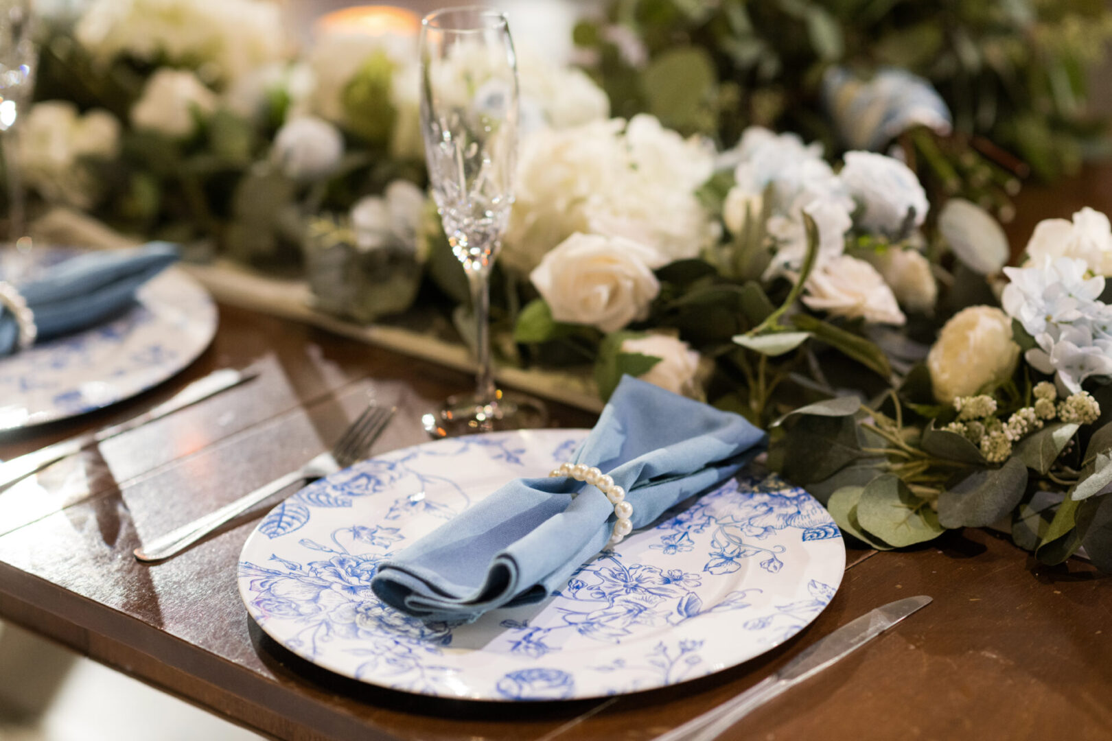 Blue floral charger with napkin and pearls.