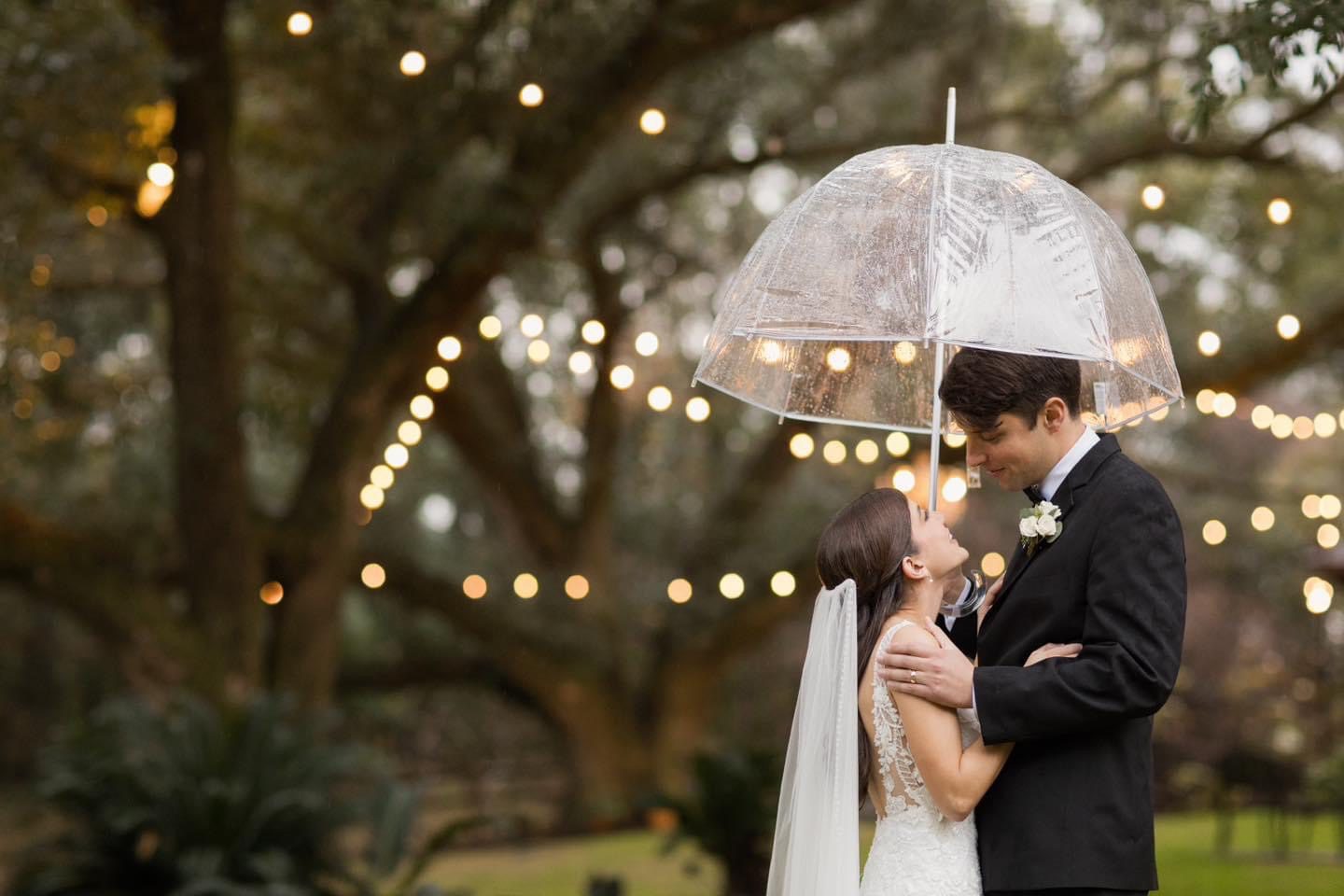 Bride and groom kissing under umbrella.