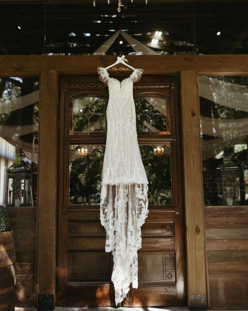 Lace wedding dress hangs on door.