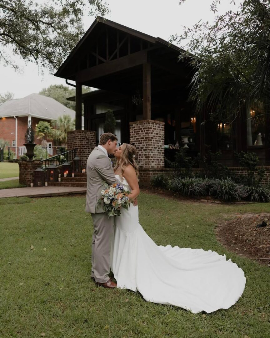 Bride and groom kissing by house.