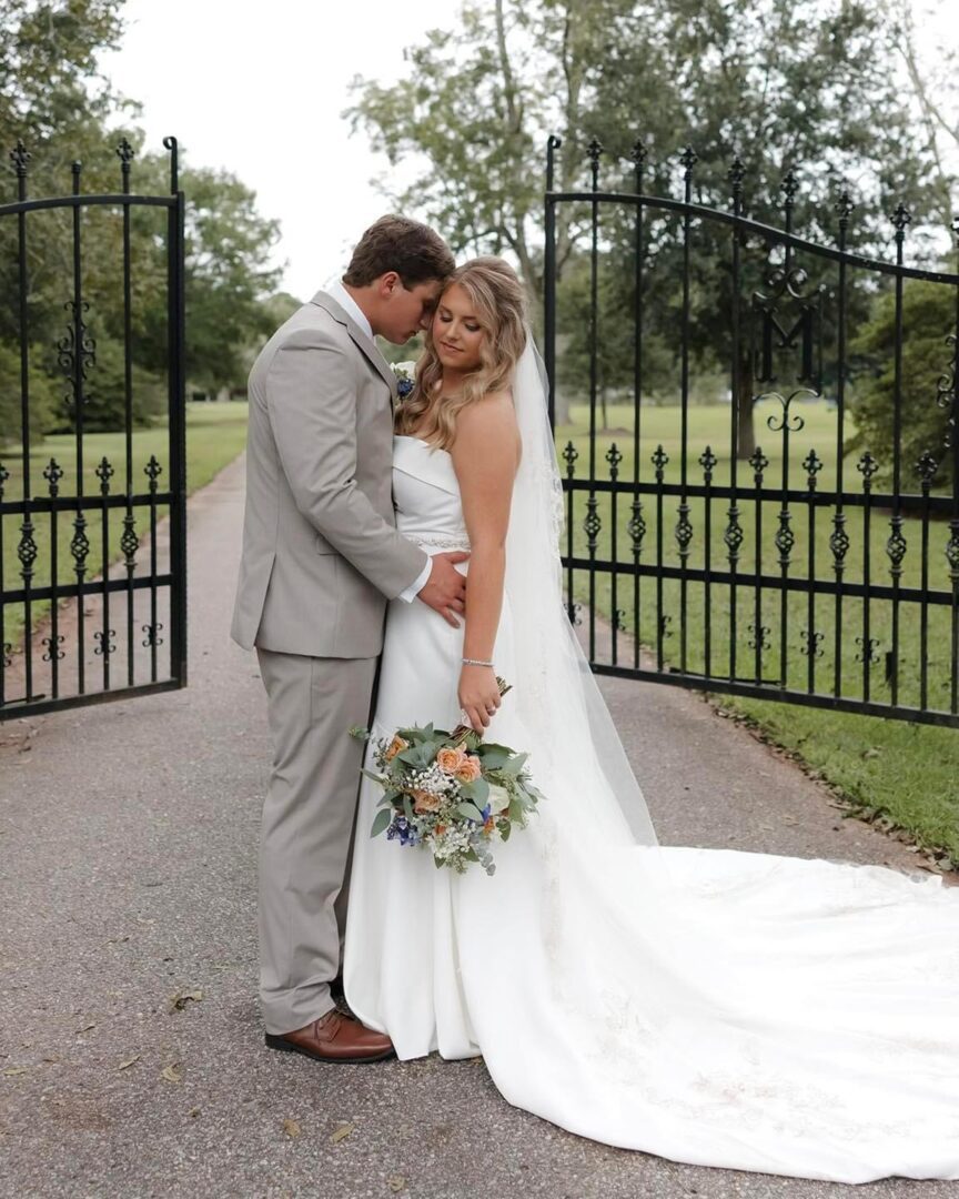 Bride and groom embrace at gate.
