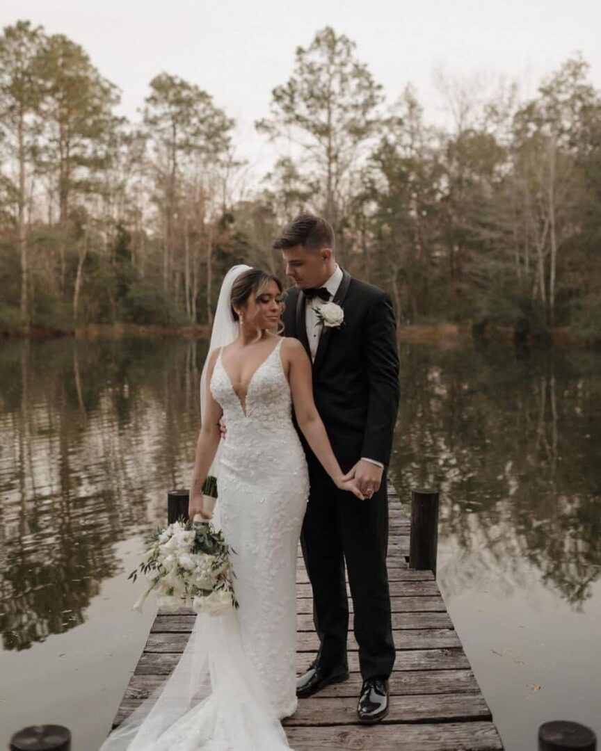 Bride and groom on a dock by lake.