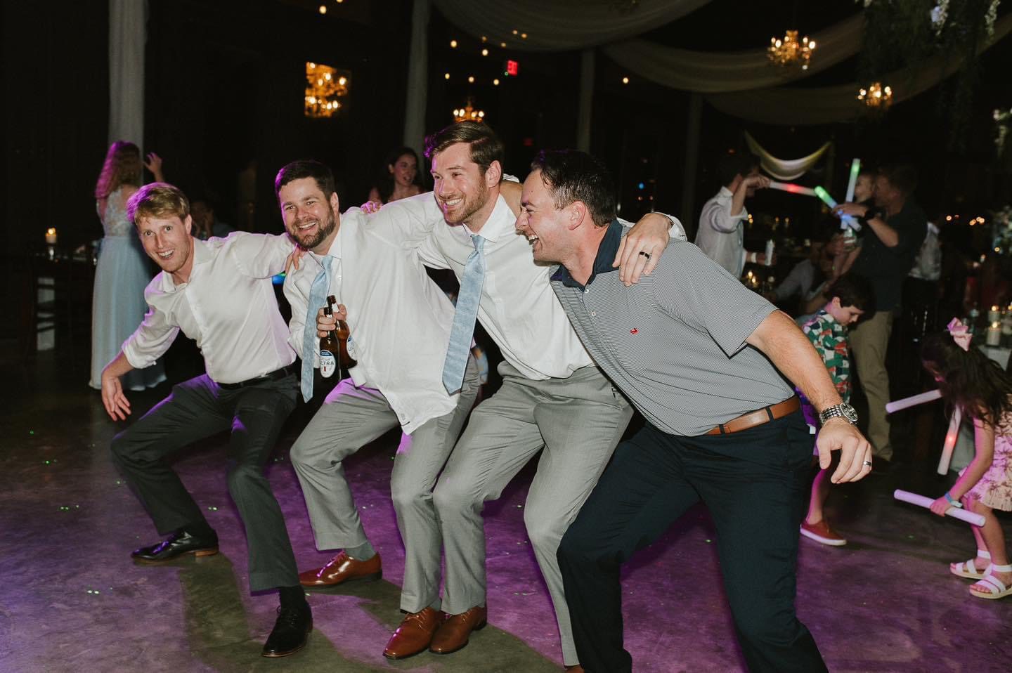Four groomsmen dancing at a wedding.