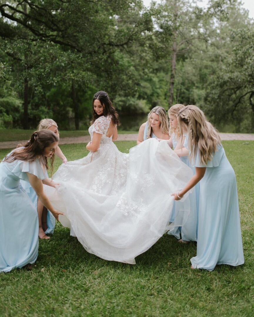 Bridesmaids holding bride's wedding dress.