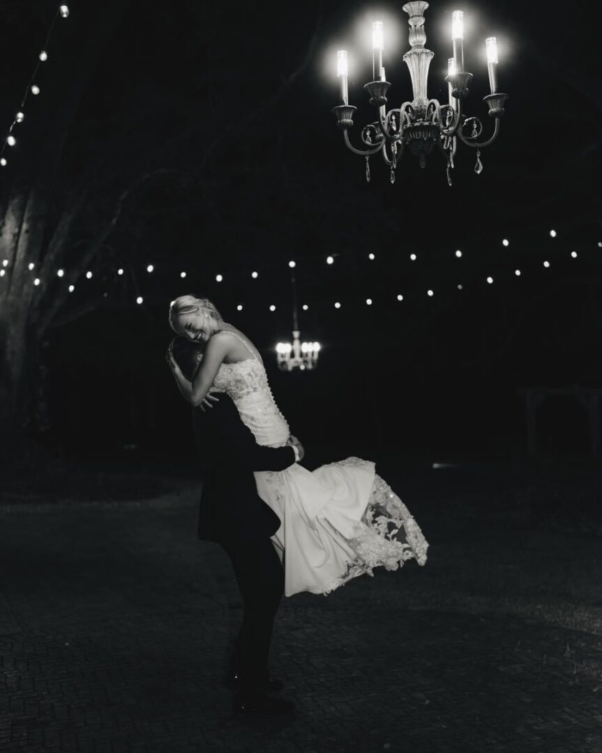 Groom lifts bride at night wedding.