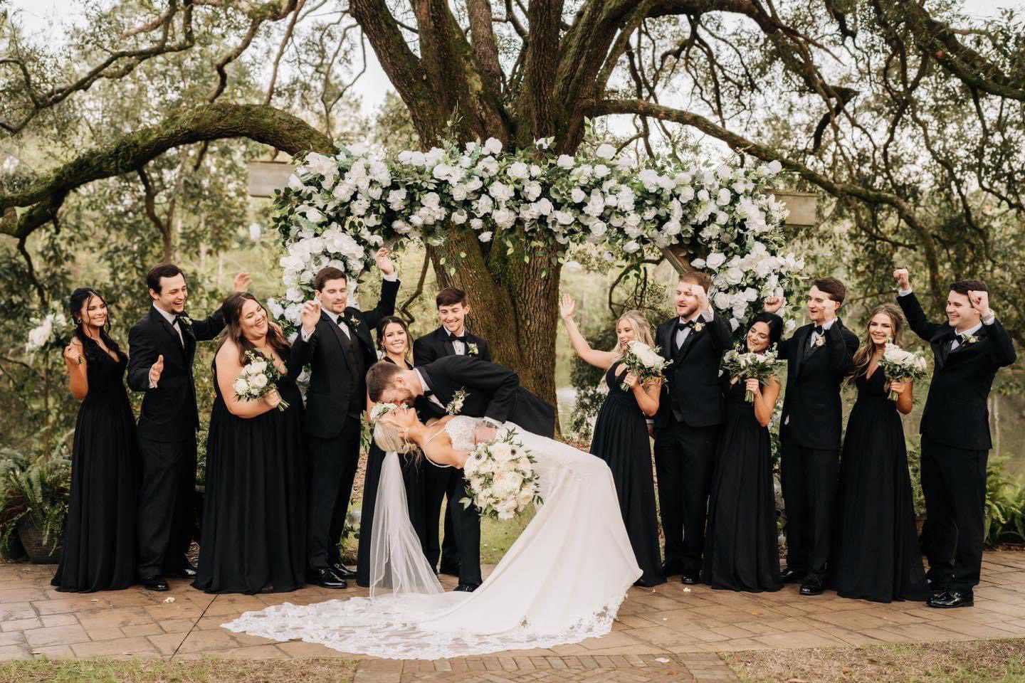 Bride and groom kiss, wedding party cheers.