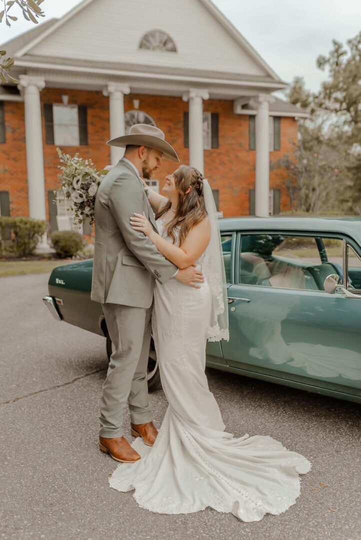 Bride and groom embrace by classic car.