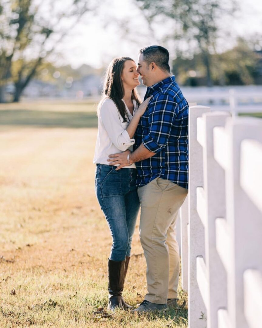 Couple embracing near a white fence.