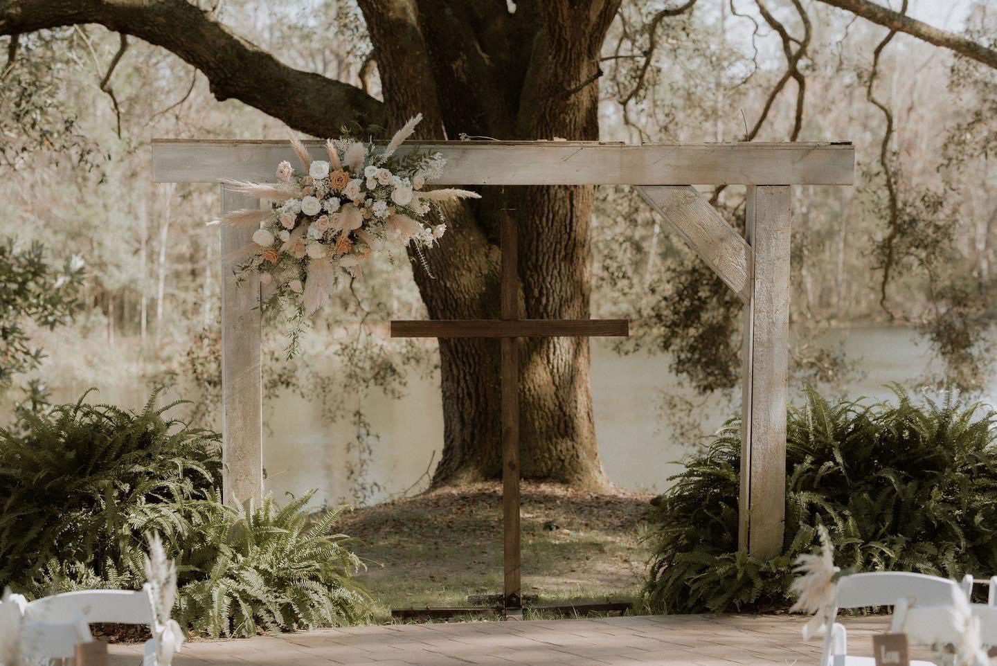 Rustic wedding arch with cross and flowers.