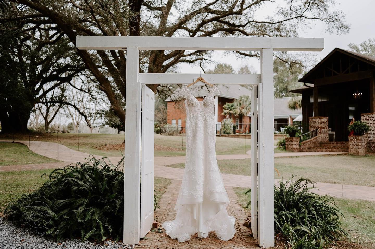 Wedding dress hanging in white doorway.