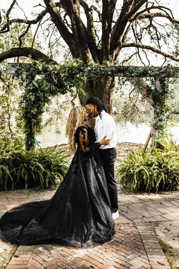 Couple in black wedding attire embracing.