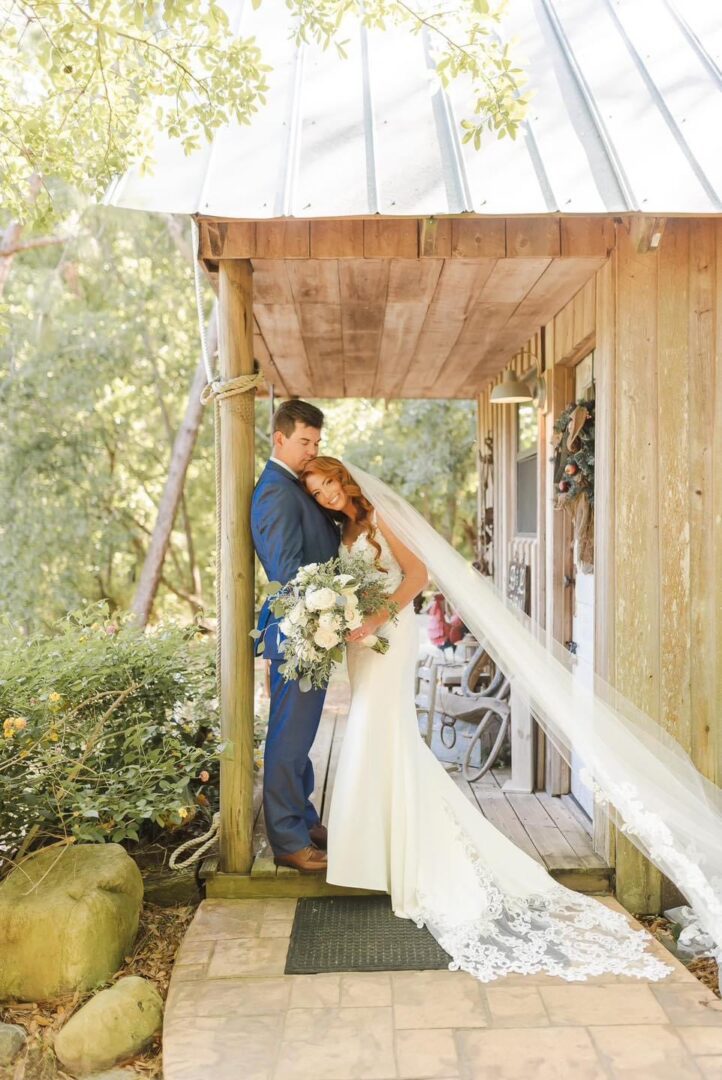 Bride and groom embrace on porch.