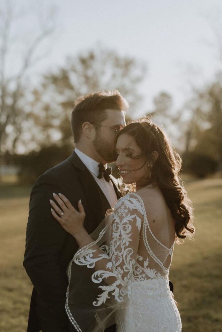 Groom kissing bride on forehead, outdoor.