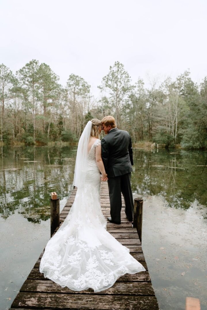 Bride and groom on a dock by a lake.
