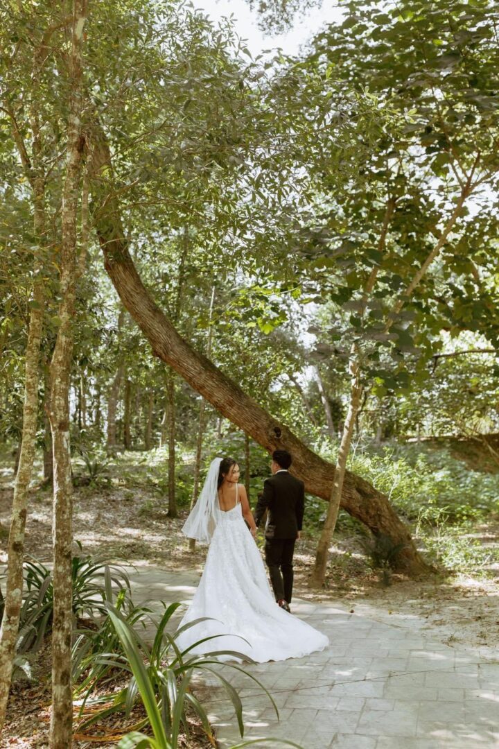 Bride and groom walking in woods.