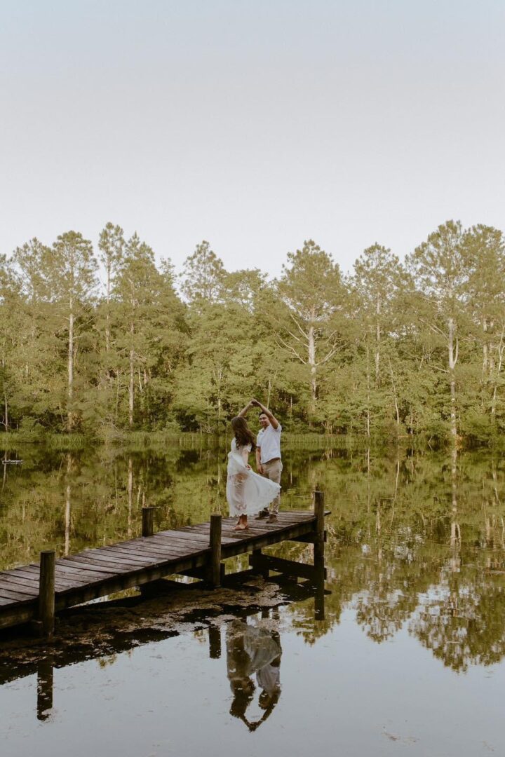 Couple dancing on a lake dock.