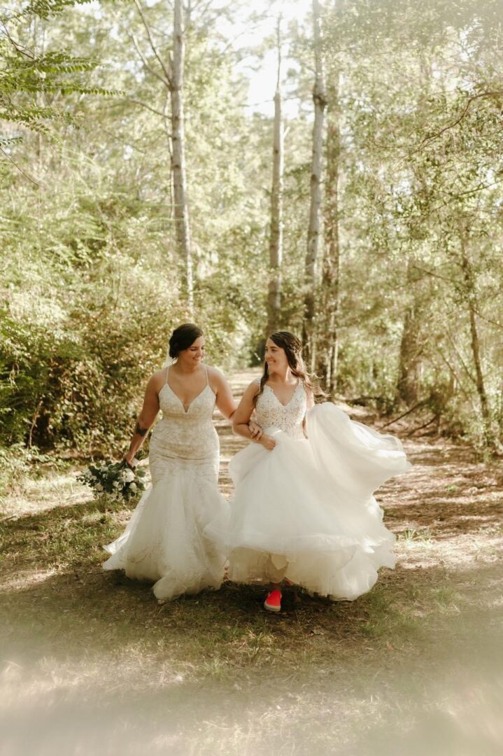 Two brides walking in a forest.