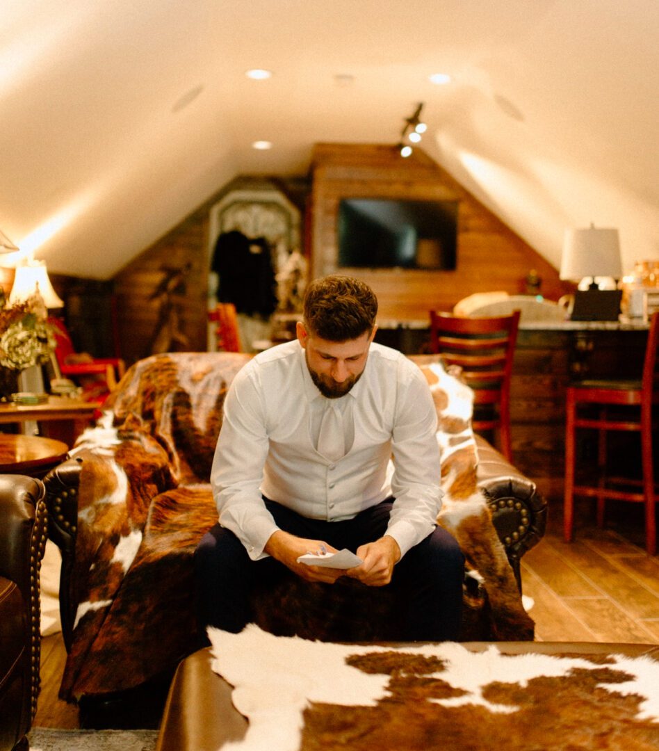 Groom reading letter on cowhide couch.