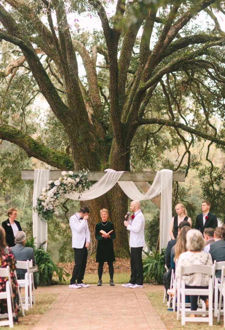 Outdoor gay wedding ceremony under a tree.