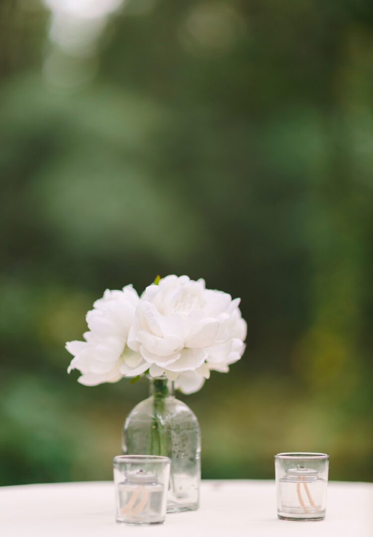 White flowers in vase, candles on table.