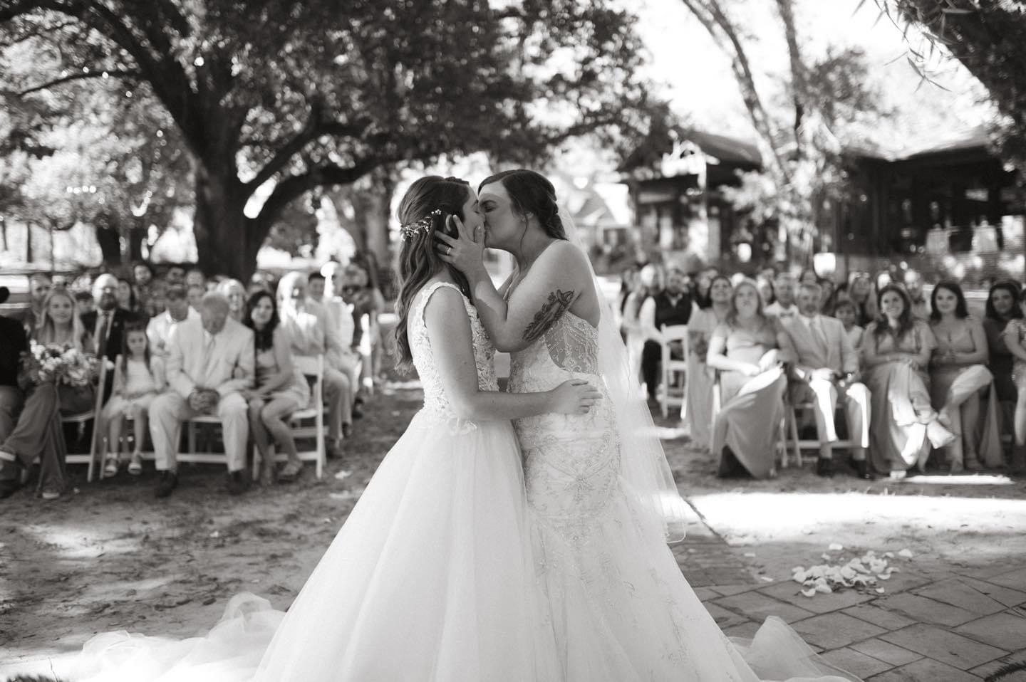 Brides kissing at wedding ceremony.